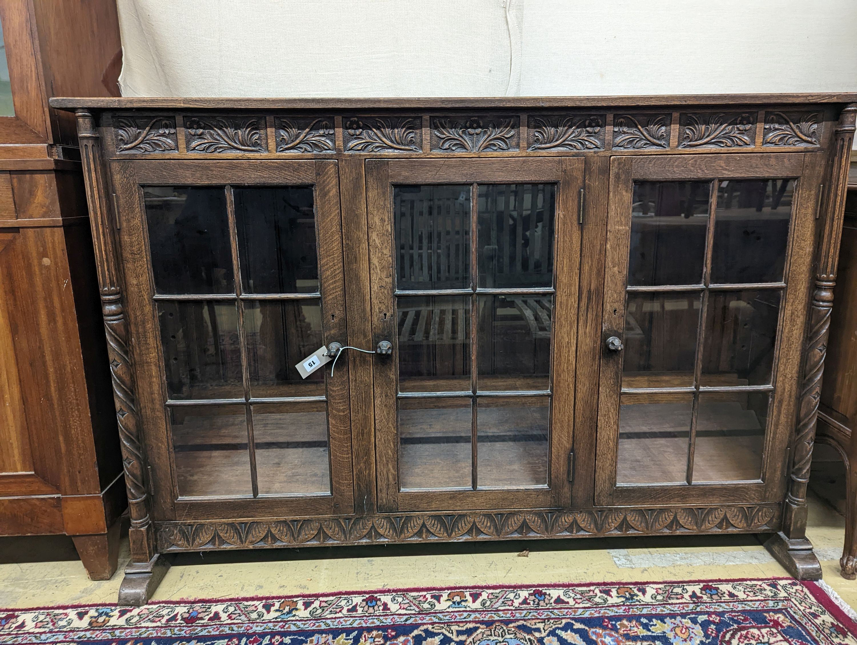 A 17th century style oak glazed low bookshelf. W-152cm, D-38cm, H-100cm.